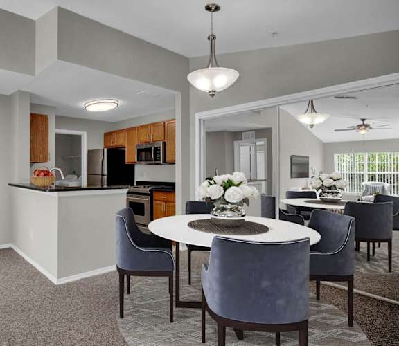 a dining area with a table and chairs and a kitchen in the background