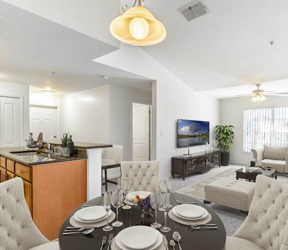 a living room with a dining table and a kitchen in the background