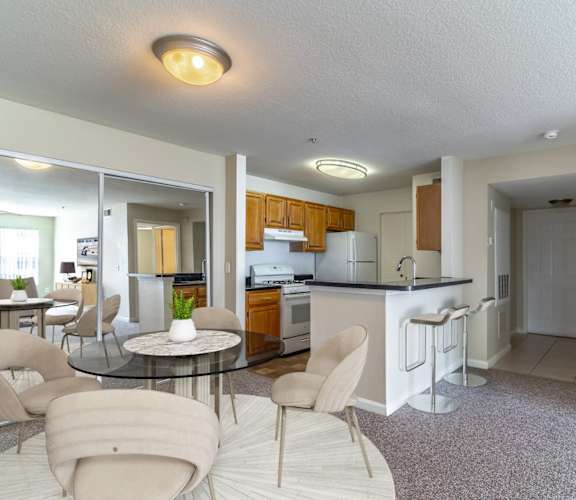 a living room with a table and chairs and a kitchen in the background