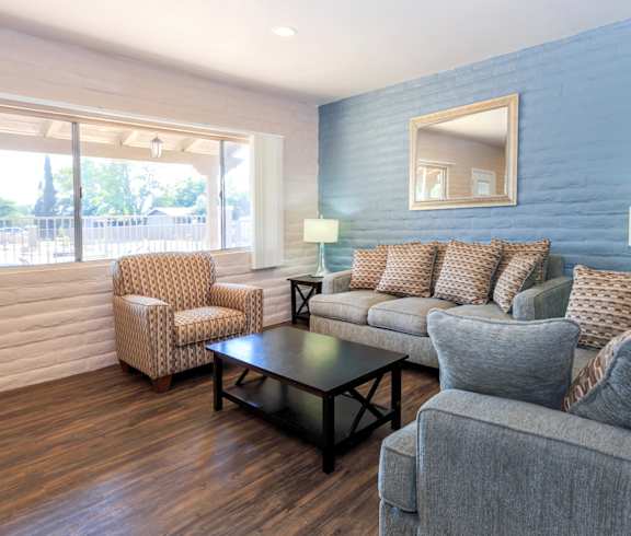 A living room with a grey couch, a brown chair, and a black coffee table.