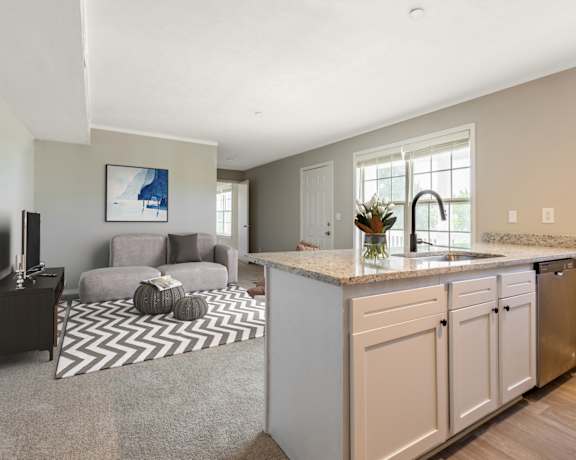 a kitchen with an island and a living room in the background