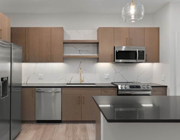 A modern kitchen with a stainless steel refrigerator, microwave, and oven.
