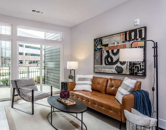 a living room with a leather couch and a table at Centro at Pine Nash in Wilson, NC 27893