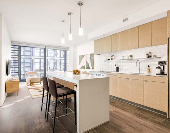 a kitchen with light wood cabinets and a large island with a white countertop