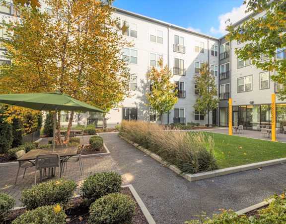 A courtyard with a green umbrella and a building in the background.