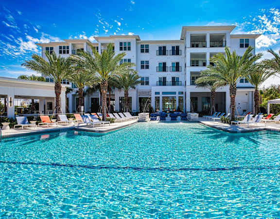 A large white building with a pool in front of it. at Altis Twin Lakes Apartments, Kissimmee, FL 34744