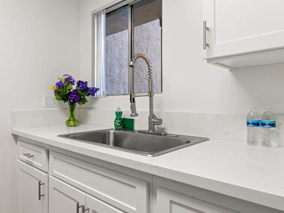 A kitchen with a table and chairs in front of a fridge and cabinets.