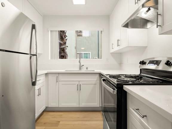A kitchen with a table and chairs in front of a fridge and cabinets.