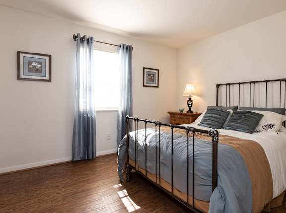 A bedroom with a bed, nightstand, and two pictures on the wall.