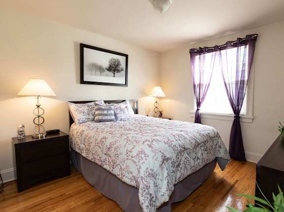 A bedroom with a large bed and a painting on the wall.