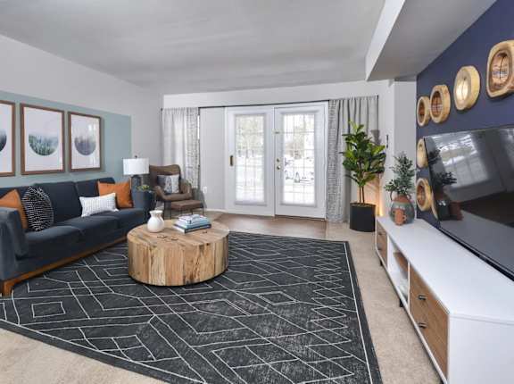 A living room with a grey couch, a wooden coffee table, and a black and white rug.
