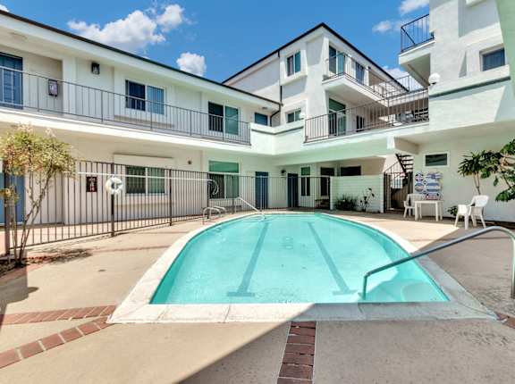 a swimming pool sits in front of a white building with a pool