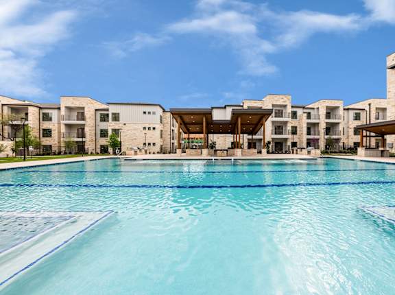 a large swimming pool with apartments in the background