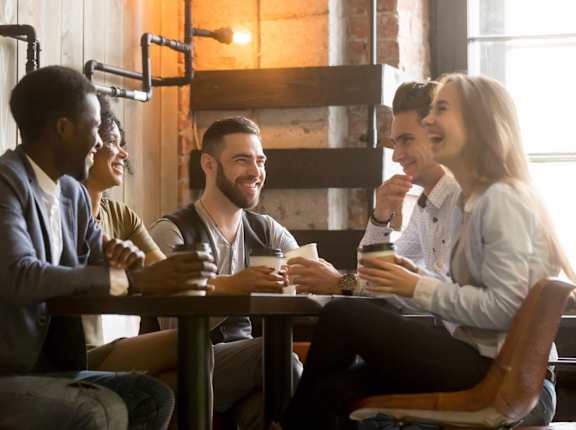 Friends Smiling and Laughing while Having Coffee Together