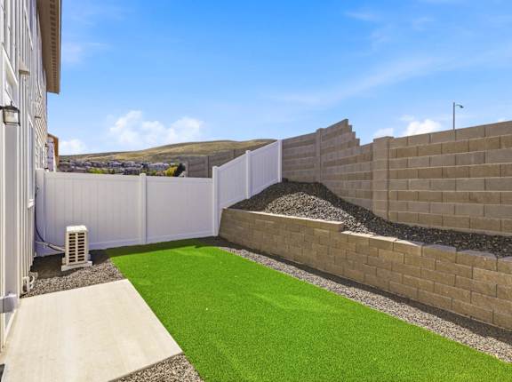 A backyard with a white fence and a green lawn.