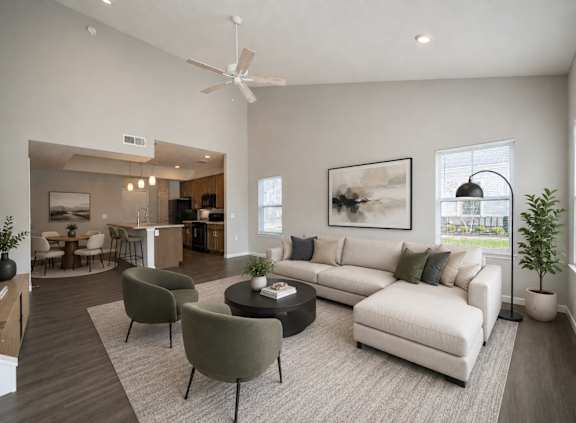 A living room with a white couch, a grey armchair, a coffee table, and a ceiling fan.