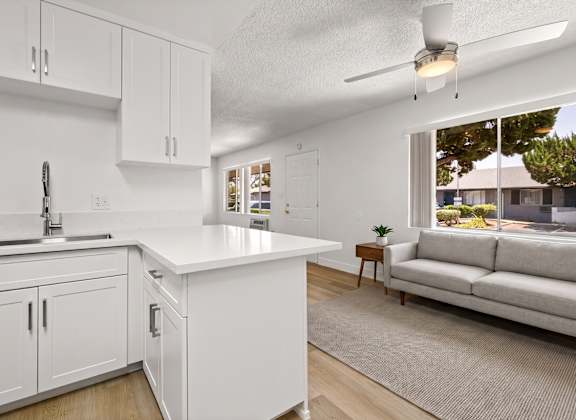 A white kitchen with a couch and a window.