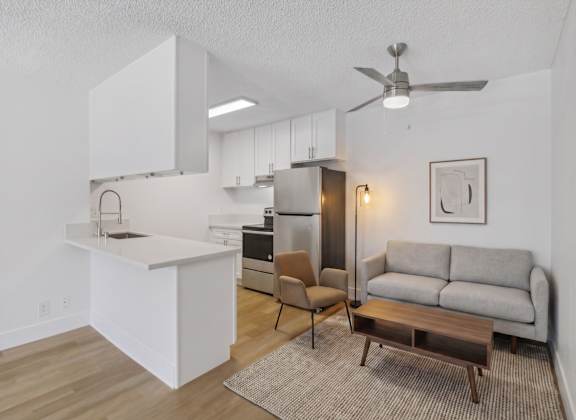 A modern kitchen with white cabinets and a wooden floor.