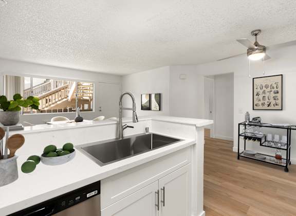 A kitchen with white cabinets and a stainless steel sink.