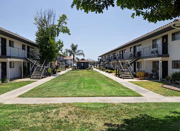 A row of apartment buildings with green lawns in front.