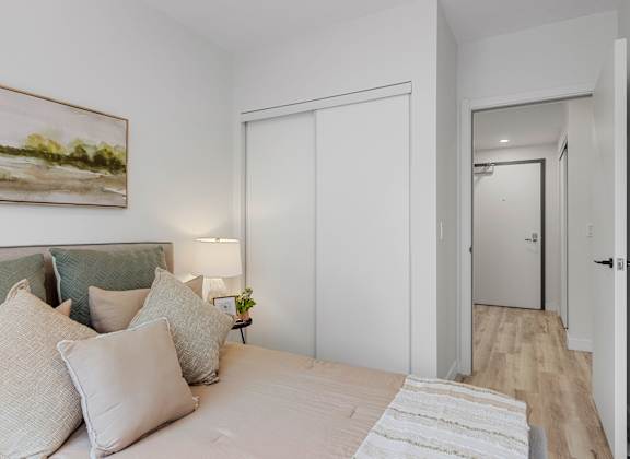 A bedroom with a bed, pillows, a lamp, and a painting on the wall.