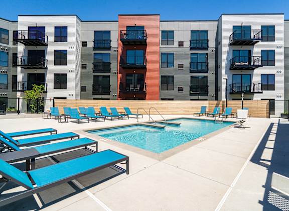 Community outdoor pool surrounded by blue pool chairs