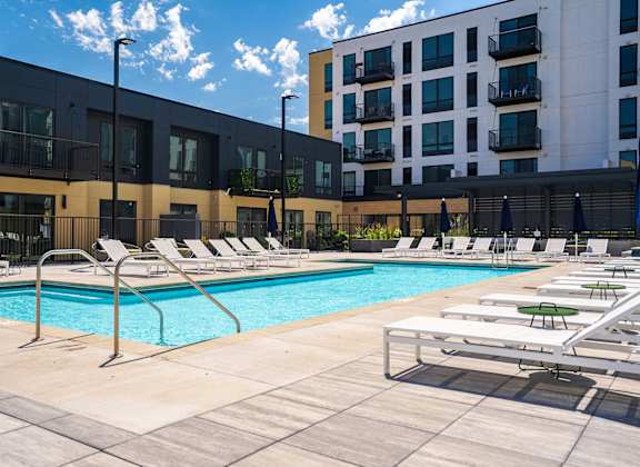 a swimming pool with chaise lounge chairs and a building in the background