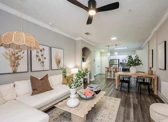 A living room with a white couch, a wooden coffee table, and a ceiling fan.