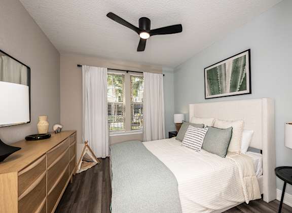 A bedroom with a bed, nightstand, and a ceiling fan.