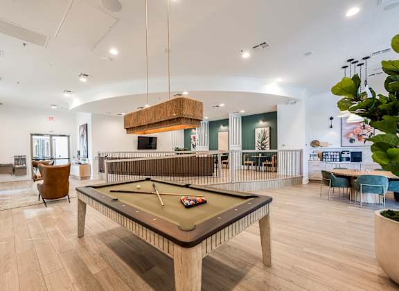 A billiard table is in the middle of a room with a pool table and a snooker table.