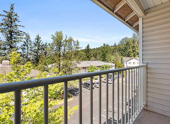 a balcony with a view of a parking lot and trees at Mill Pond Apartments, Auburn