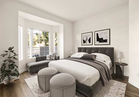 A bedroom with a large bed and a potted plant.