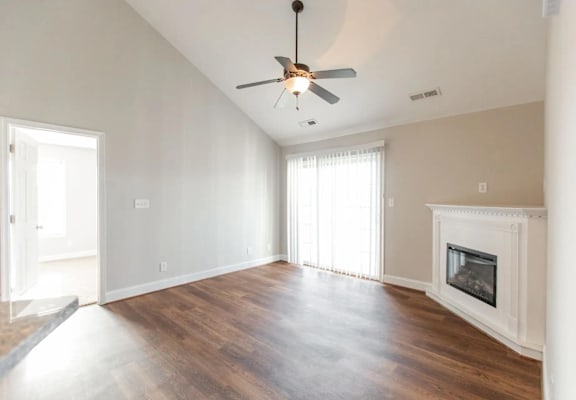 an empty living room with a ceiling fan and a fireplace