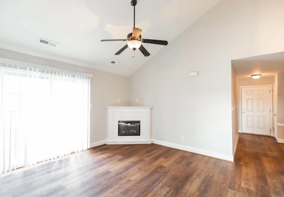 an empty living room with a ceiling fan and a fireplace