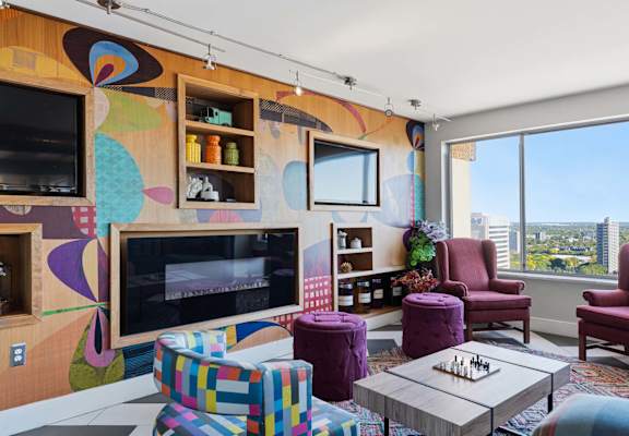 A living room with a colorful mural on the wall and a chess board on the coffee table.