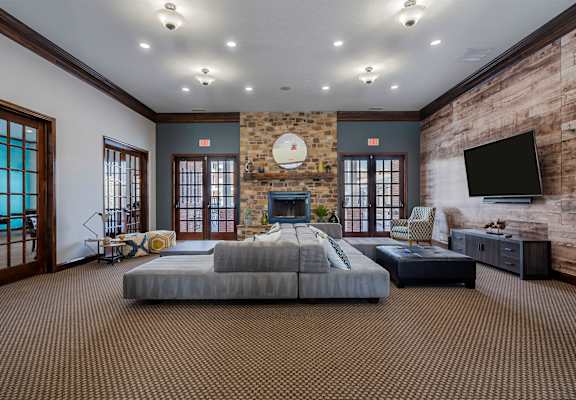 A large bedroom with a stone fireplace and a flat screen TV mounted on the brick wall.
