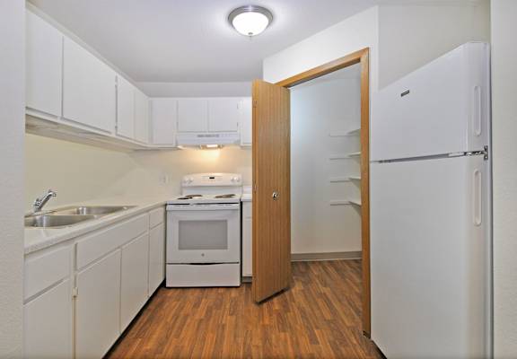 a kitchen with white cabinets and appliances and a refrigerator