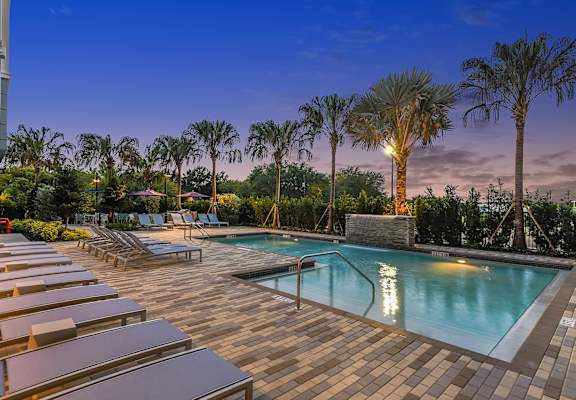 a swimming pool with lounge chairs and palm trees in the background  at The Exchange in St Petersburg 33705
