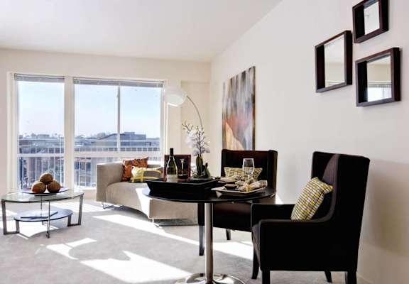 A living room with a table and chairs and a view of the city.