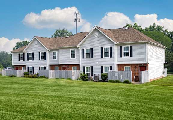 A white house with a brown roof and a fence.