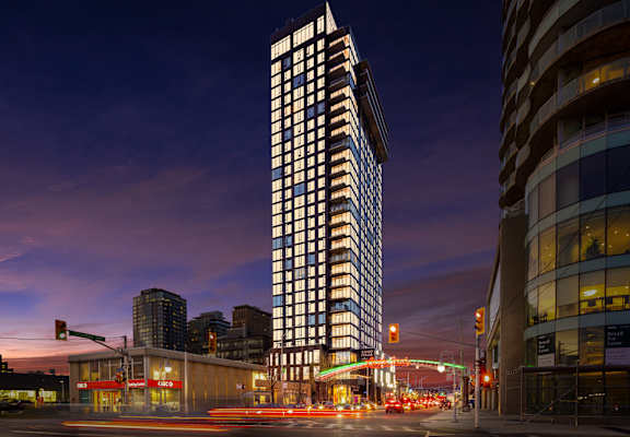 A tall building with a lot of windows stands in the middle of a city street.