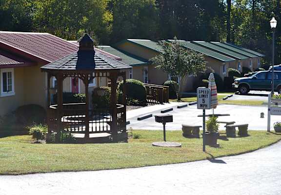 A gazebo is in the middle of a grassy area in front of a house.