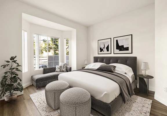A bedroom with a large bed and a potted plant.