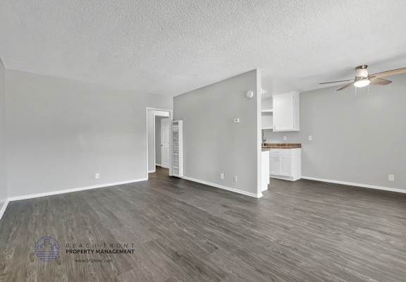 A spacious room with wooden flooring and a ceiling fan.