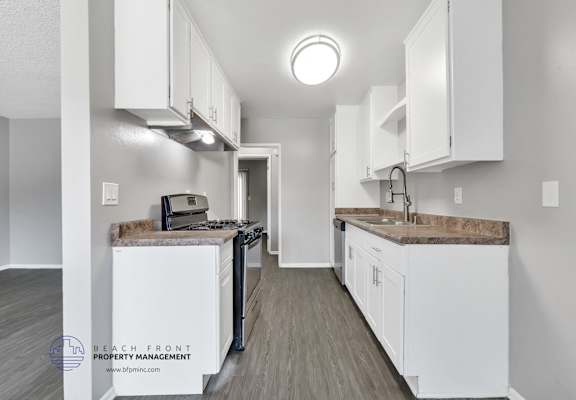 A kitchen with white cabinets and a wooden floor.