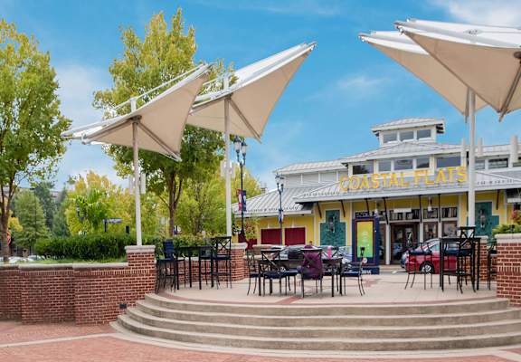 a patio with tables and umbrellas in front of a building
