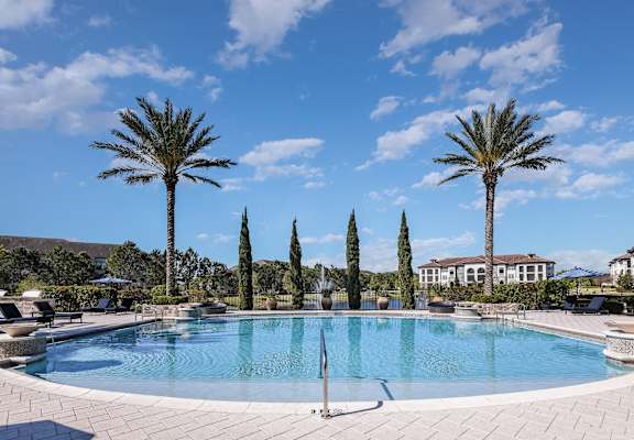 a swimming pool with palm trees in front of a hotel