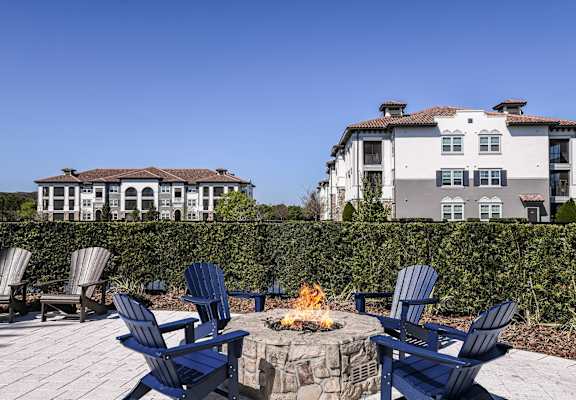 a patio with blue chairs and a fire pit