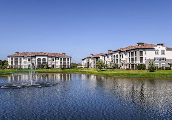 three apartment buildings on the side of a pond