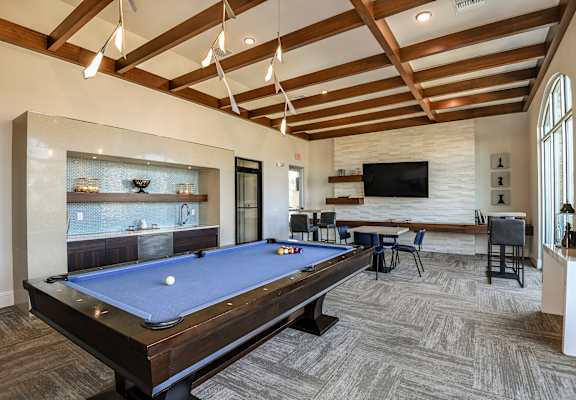 a pool table in a clubhouse with a bar and a tv